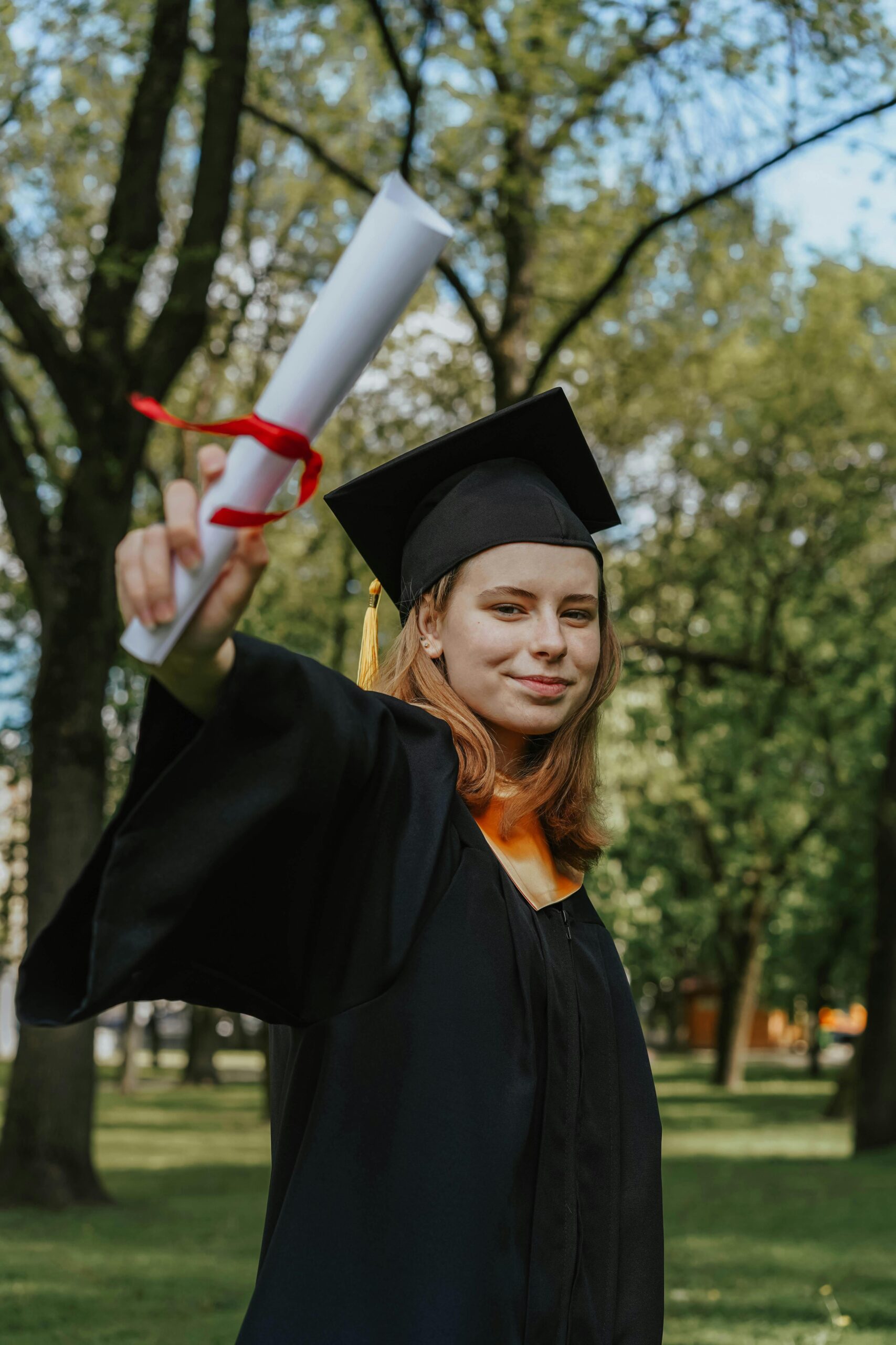 <font dir="auto" style="vertical-align: inherit;"><font dir="auto" style="vertical-align: inherit;">Lar</font></font> Cheerful young woman holding a diploma and celebrating graduation in a sunny park.